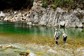 Two people wearing waders fly fishing in the middle of Owen River.